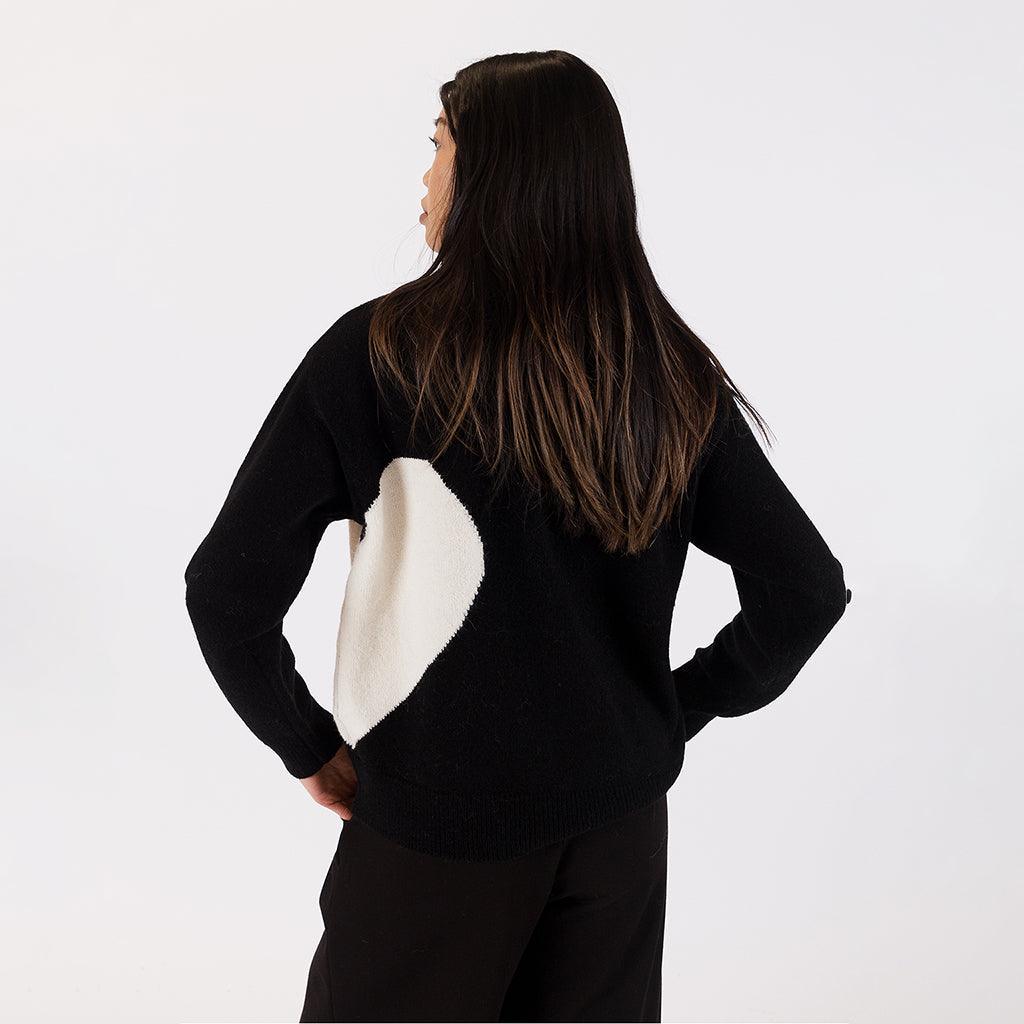 The mock neck style adds a touch of sophistication while providing warmth and comfort. The contrasting black and off-white colors create a striking visual appeal, making it a versatile piece that pairs effortlessly with various outfits. 