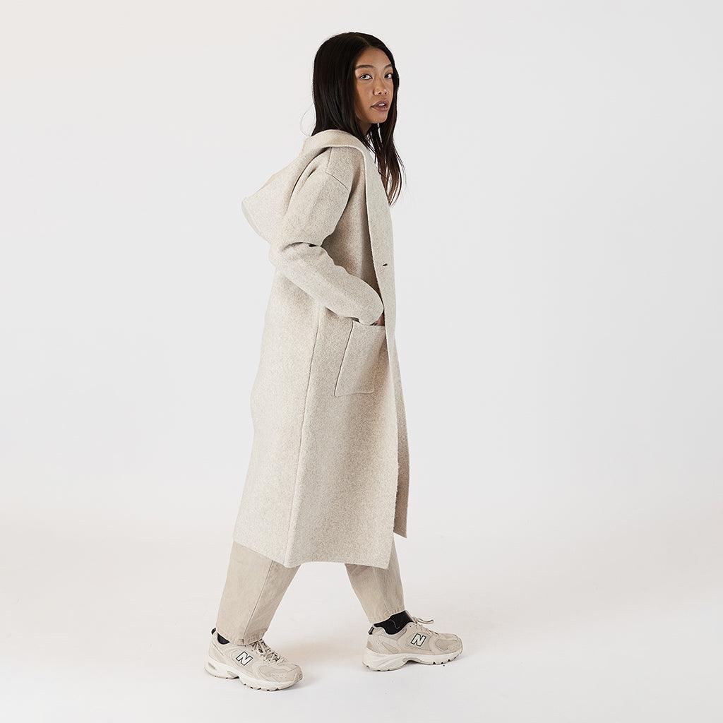 Introducing the Long Hooded Coat in Beige – a true fall closet essential that combines style and functionality seamlessly. This coat boasts a netural beige colour that effortlessly blends with your existing wardrobe pieces. Featuring a button closure and two deep front pockets, it offers both practicality and fashion-forward design.