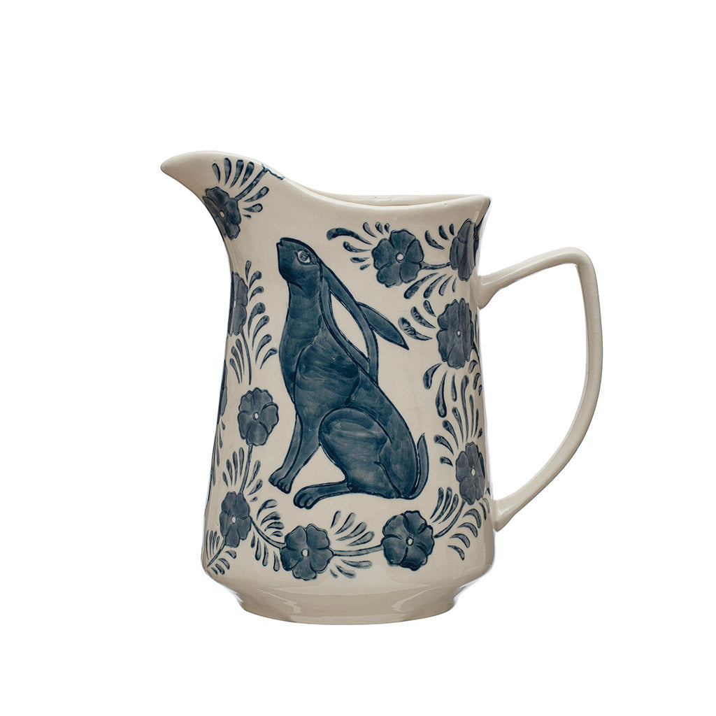 Bring a piece of nature into your home with this charming hand-painted stoneware pitcher. The intricate rabbit and floral design in blue and white adds a whimsical touch to your kitchen. 