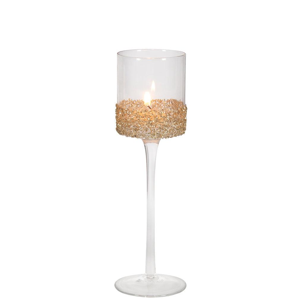 Elevate the ambiance of your space with our enchanting Clear Glass Tealight Holder. This medium-sized candle holder stands tall on a stem, measuring 9.75 inches in height. It features a stylish gold glass glitter band that adds a touch of sparkle and sophistication to your décor. 